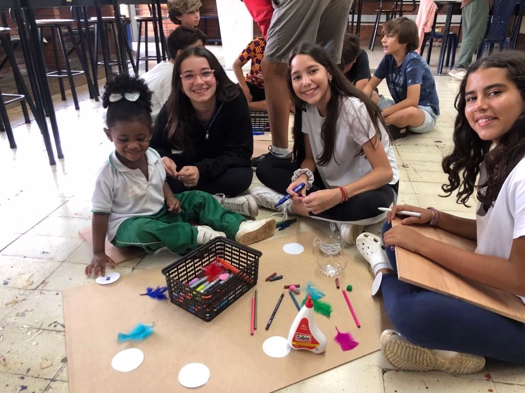 Estudiantes haciendo manualidades con niña pequeña